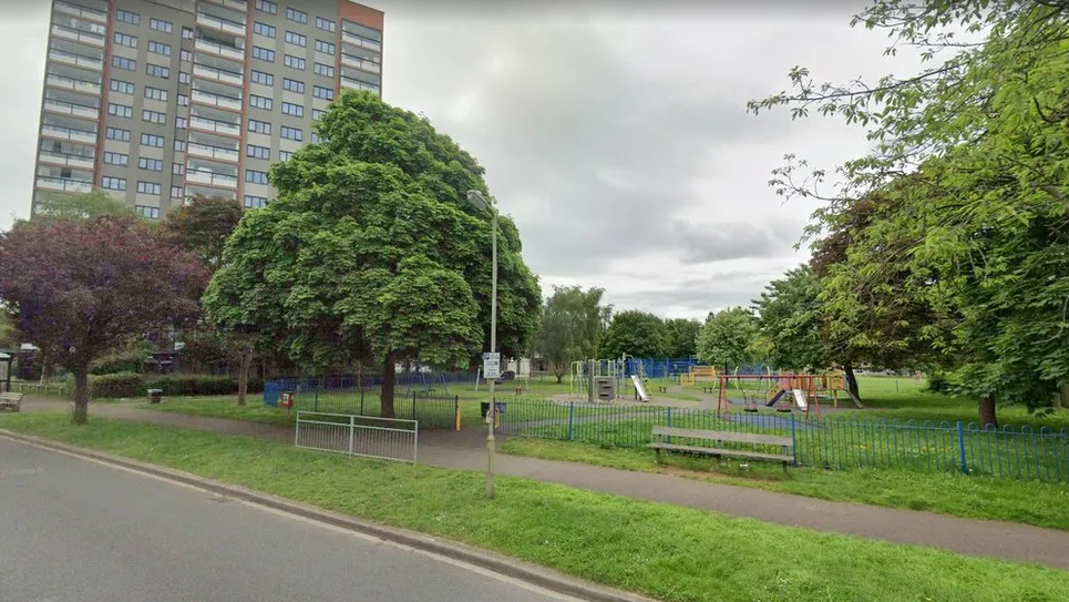 Wood Farm Park, with several trees and a play area in a fenced area 