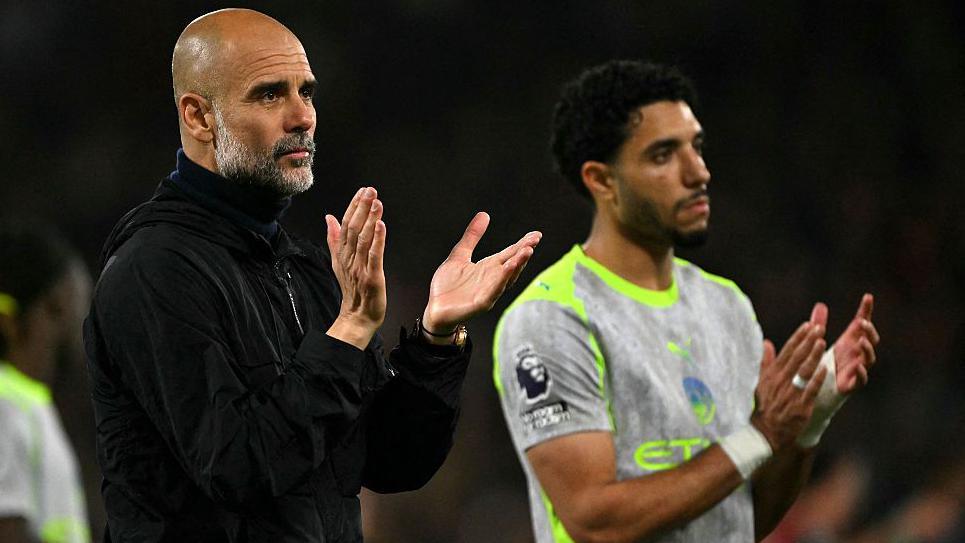 Pep Guardiola applauds the Manchester City fans while looking disappointed