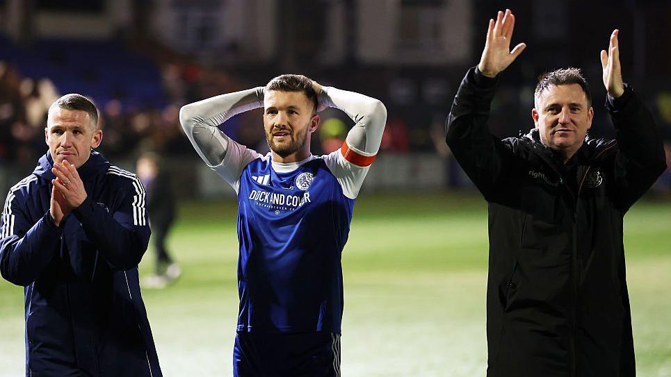 Macclesfield manager John Rooney, captain Paul Dawson and owner Rob Smethurst applaud fans after the FA Cup fourth round loss against Brentford.