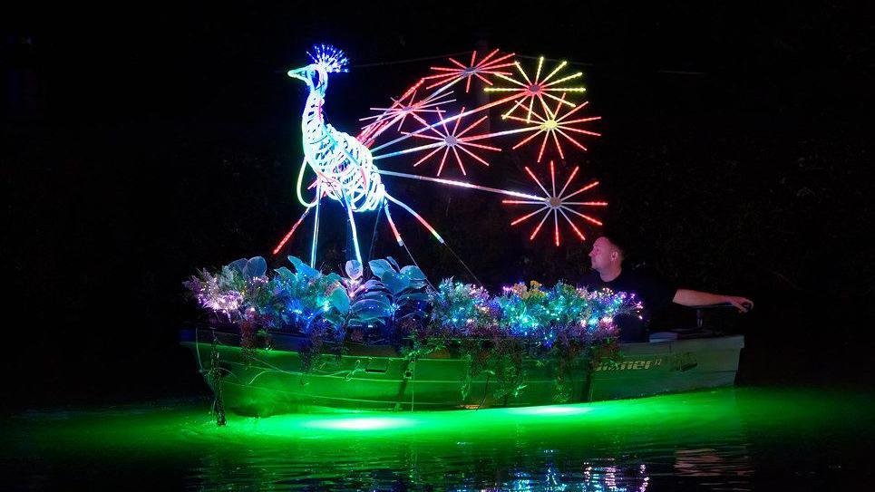 Paul Lill riding a boat with an LED peacock mounted on top