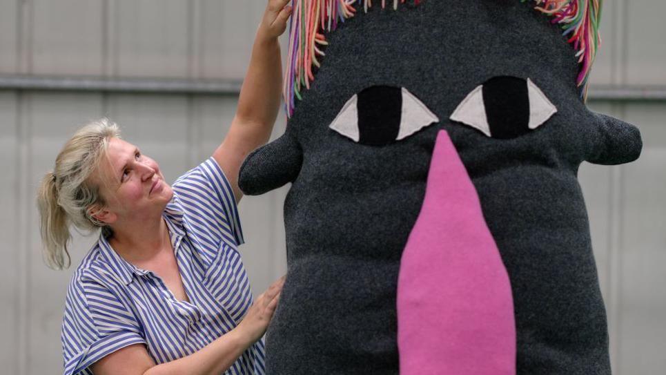 A staff member at Dundee Design Festival with a creature made from fabric