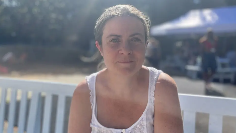 Louise looking into the camera while - wearing a white cotton top