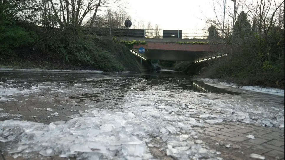 Ice and puddles can be seen leading up to and underneath the underpass