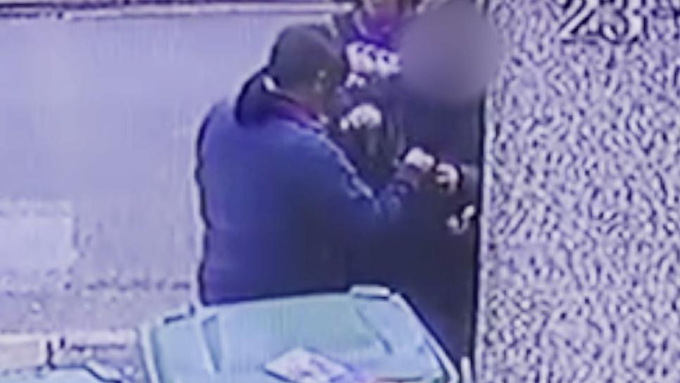 A grainy still from CCTV footage showing Tuyet’s mother handing over a plastic bag containing her valuables to be blessed by a scammer.