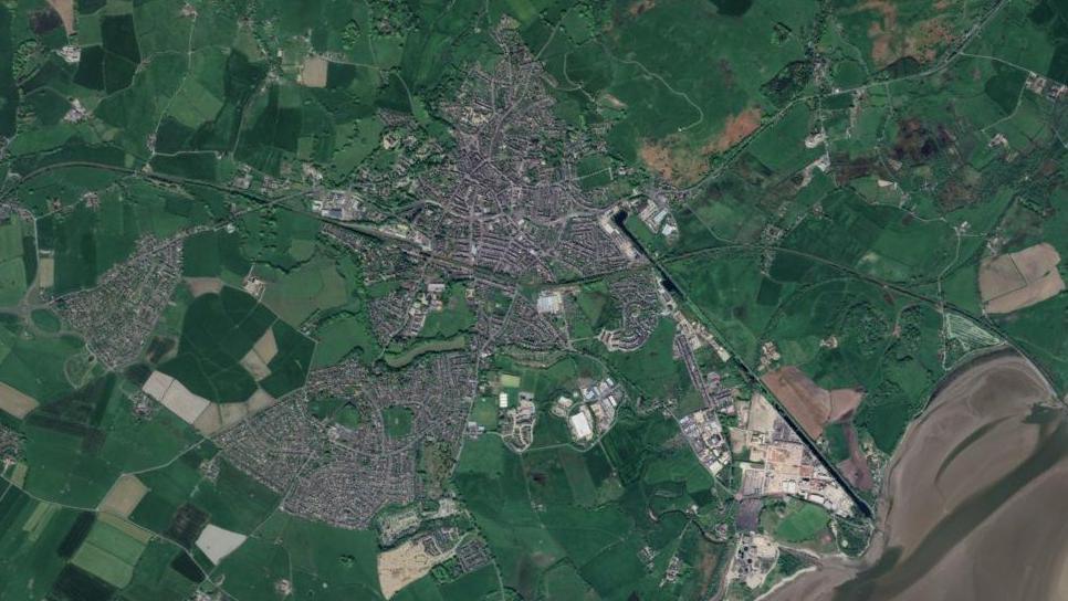 A map looking at Ulverston and its surrounding area, showing green land surrounding a grey amount of urban structures