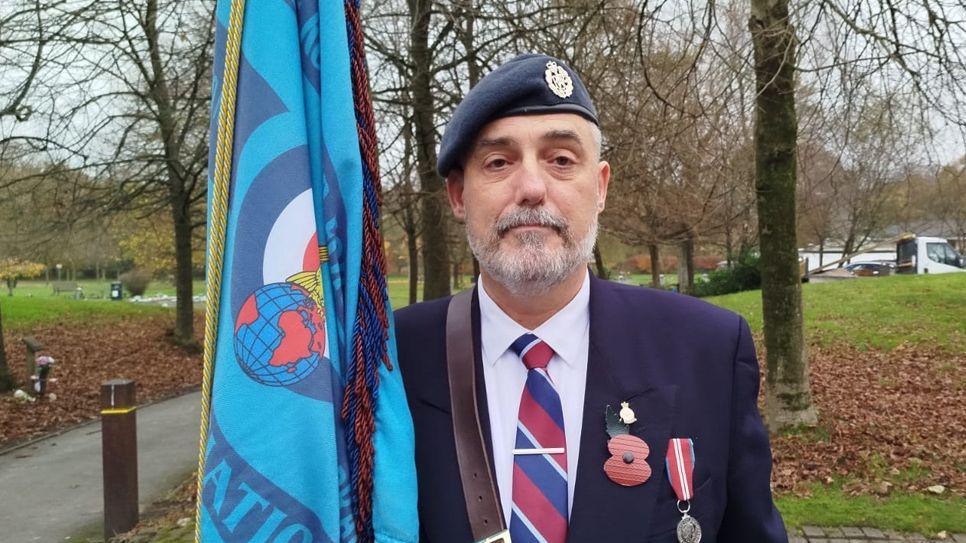 Stuart Dagger in uniform and holding a flag for the Preston branch of the Royal Air Force 