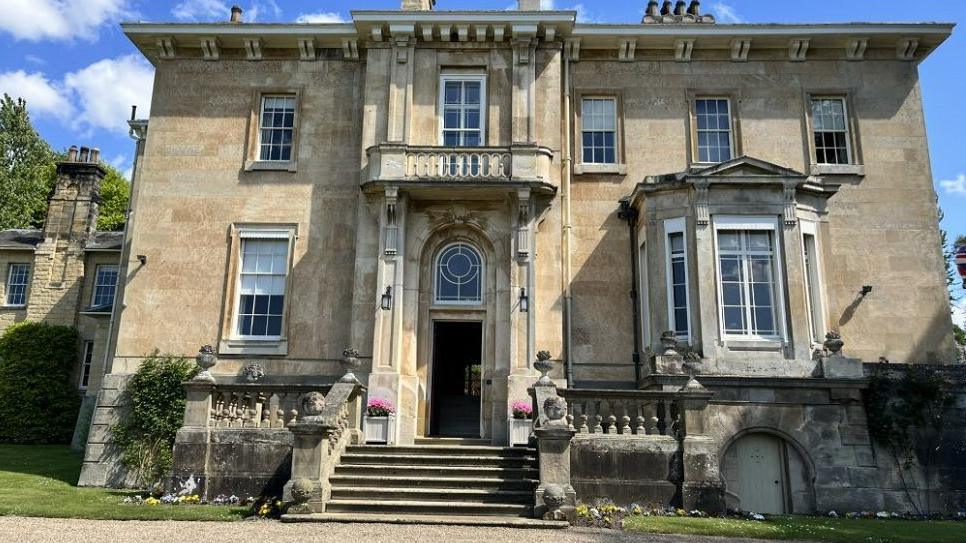 The front of Kirkham Hall, with cream coloured bricks and stairs leading up to the main house.