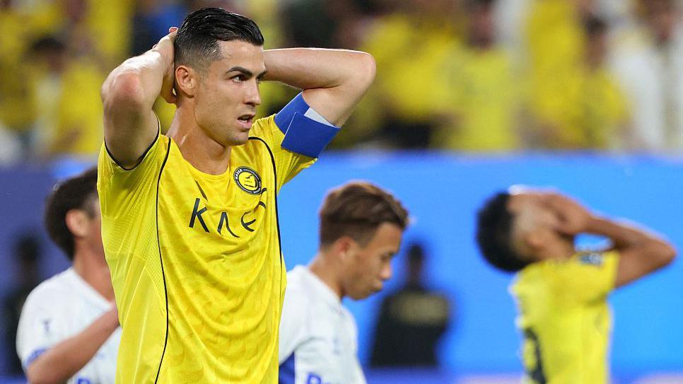 Al-Nassr's Cristiano Ronaldo looks disappointed as Gamba Osaka celebrate after winning the AFC Champions League Two final