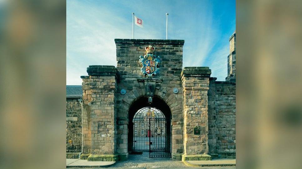 The entrance to the barracks. It is made of tall stone pillars and has a crest at the top.