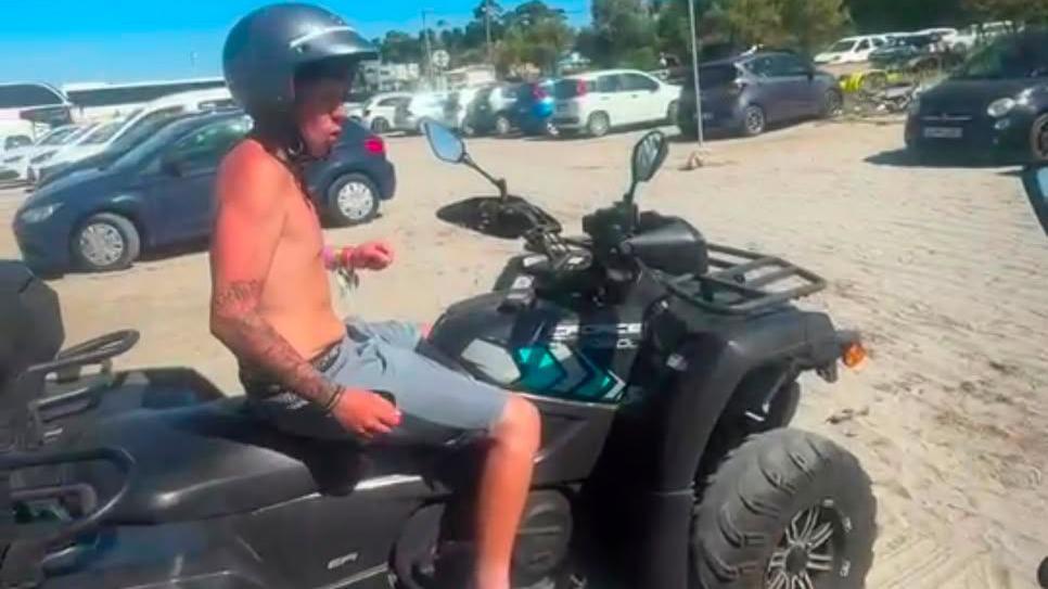 Alfie with no top on in the sunshine on a quad bike, wearing a helmet