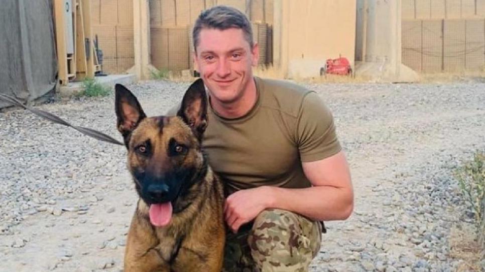 Nicholas Hart with army uniform and posing next to a dog