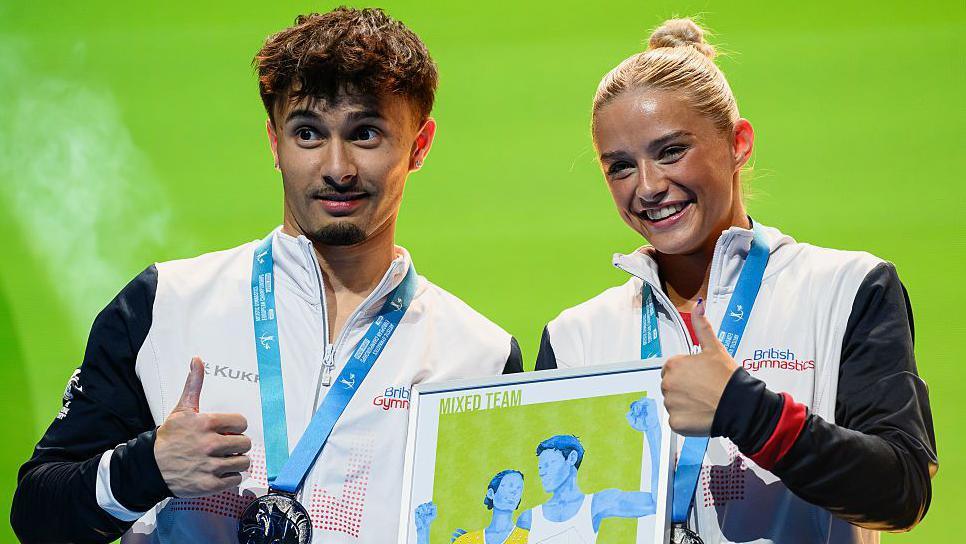 Great Britain team-mates Jake Jarman and Ruby Evans pose for a photo on the podium after winning silver at the 2025 European Artistic Gymnastics Championships