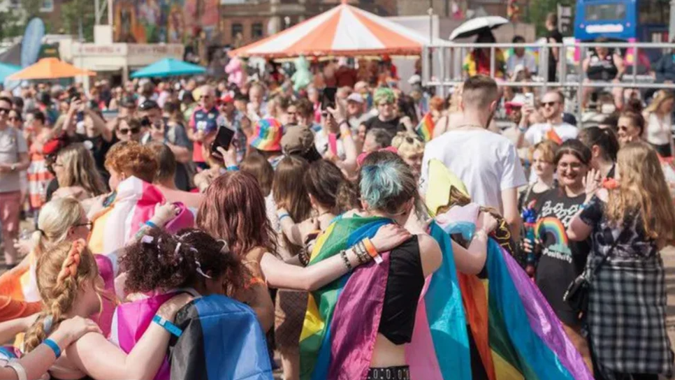 Crowds gather in the city for the party. Umbrellas can be seen along with flags draped on some revellers, some forming a "conga" line, enjoying themselves.