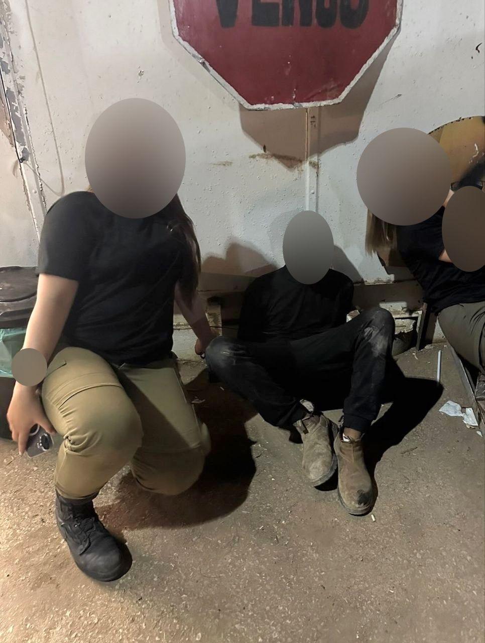 Two Israeli soldiers pose with a blindfolded man.