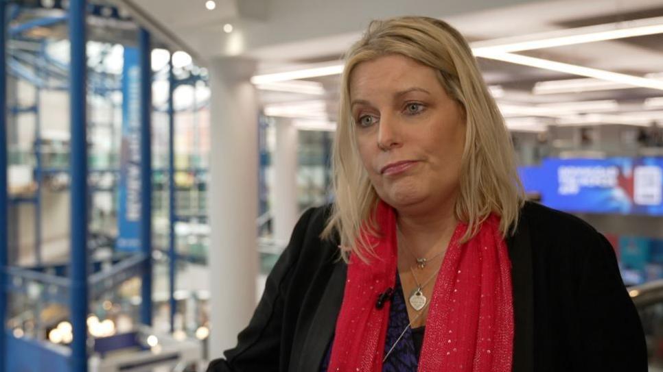 A blonde woman in a red scarf and a black jacket