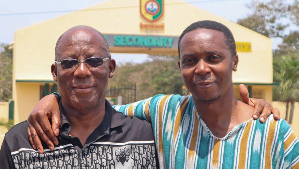 Mark Wilberforce (R) in a green, white and yellow stripped top stands outside Tema Secondary School with his Uncle Jojo