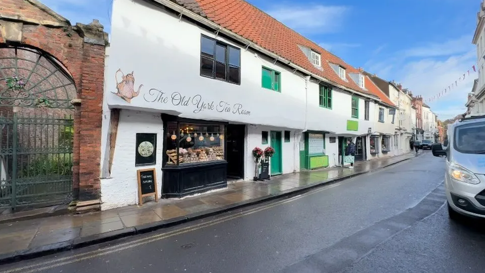 An exterior image of the tea room, which shows the painted sign and teapot image above the shop window 