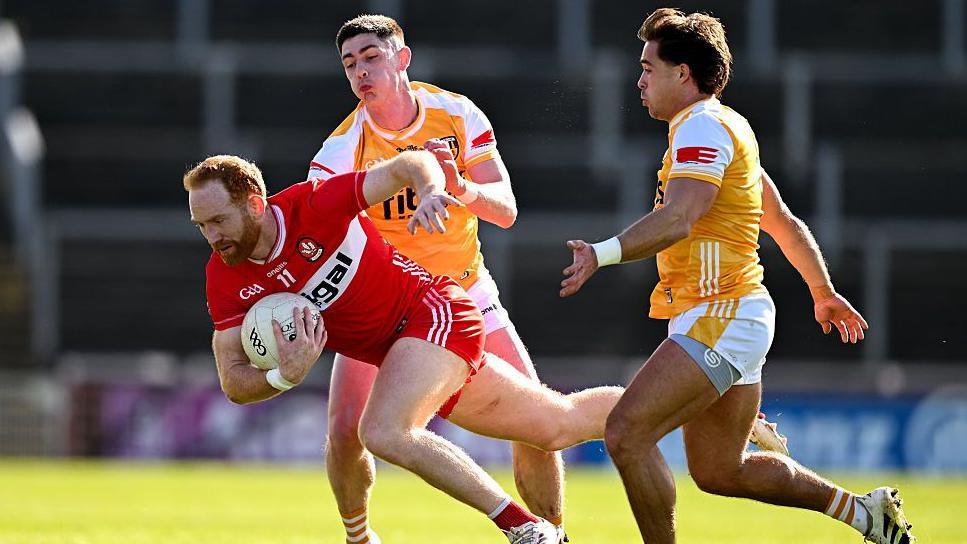 Conor Glass is challenged by Paddy McAleer and Eoghan McCabe