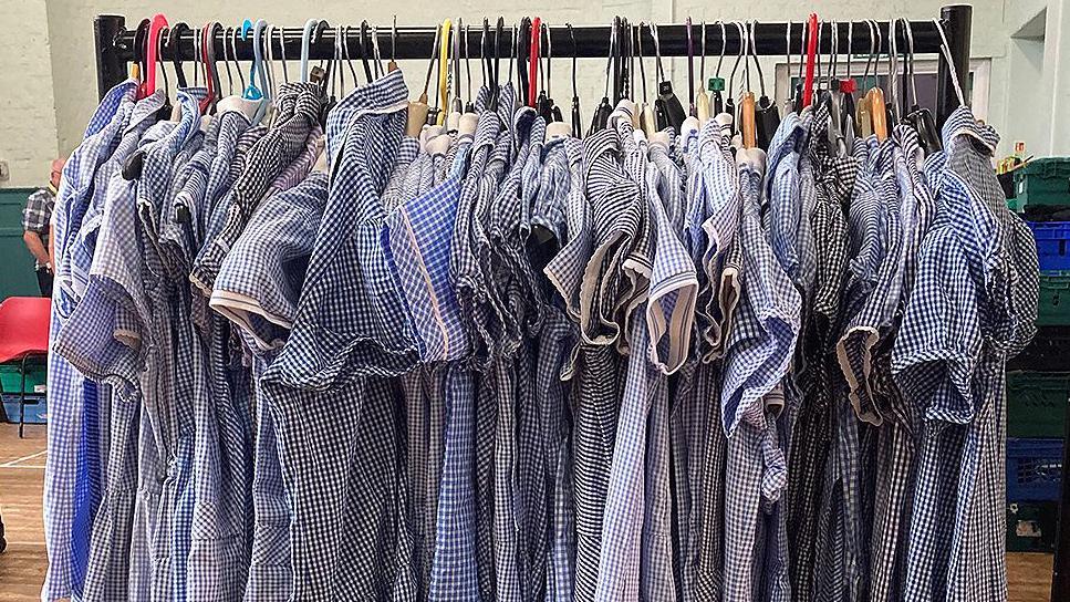 A rail full of blue and white gingham checked school dresses in various shades of blue and different styles and sizes