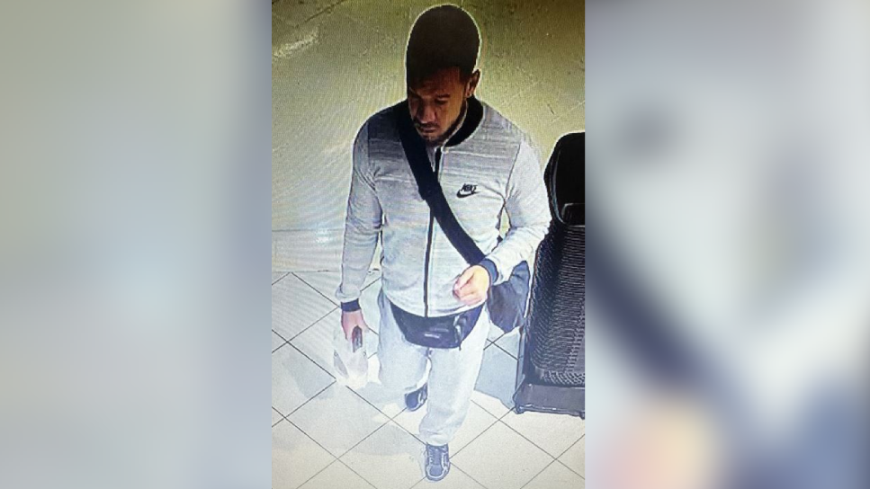 A CCTV image of a man, wearing a grey tracksuit, a dark shoulder bag and a dark bumbag