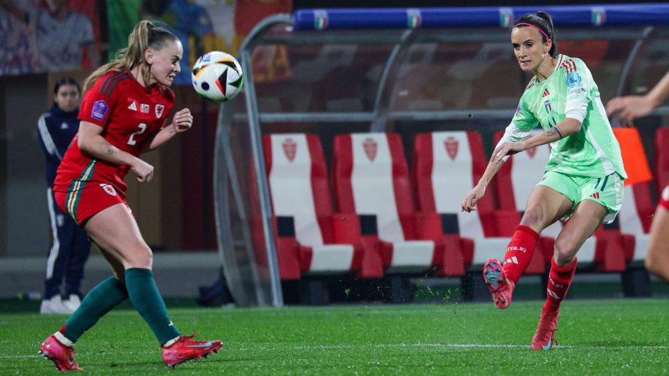 Barbara Bonansea kicking the ball while a wales player tries to intercept