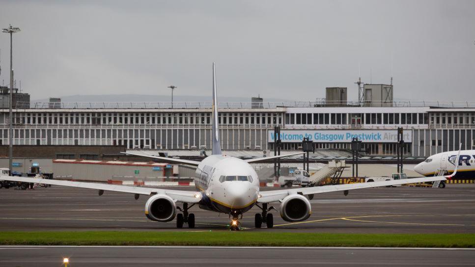 An airplane on the runway in front of the main building at Glasgow Prestwick Airport