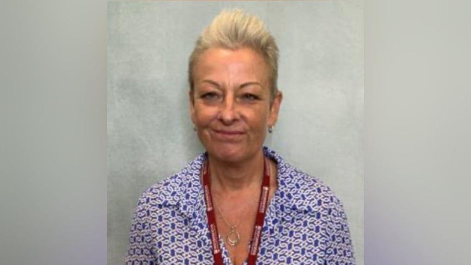 Gaynor is wearing a pattered blue and white shirt with a red council lanyard around her neck 