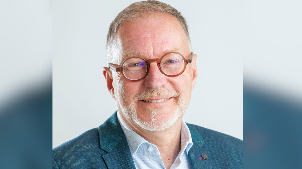 Image shows Councillor Paul Hodgkinson smiling, wearing round brown glasses, a light blue shirt, and a dark blue jacket with a small pin on the left collar.