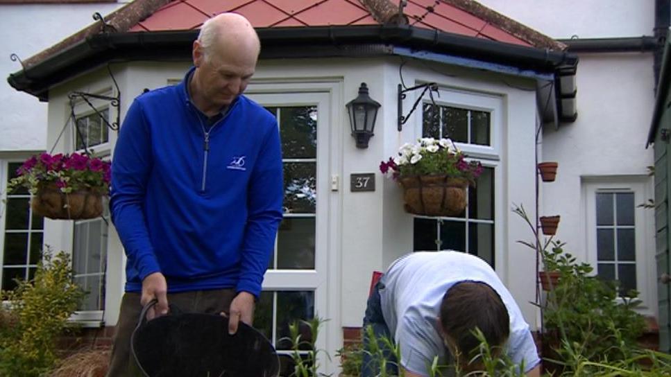 Graham and Carol gardening outside thier home