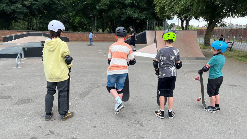 4 children standing in Norton skate park holding their skateboards