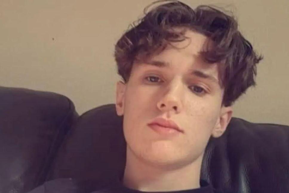 Jack Woodley has short brown hair and is sitting on a sofa looking at the camera.