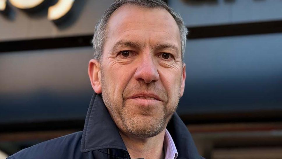 Head shot of a smiling Alistair Bradley. He has short grey hair and stubble