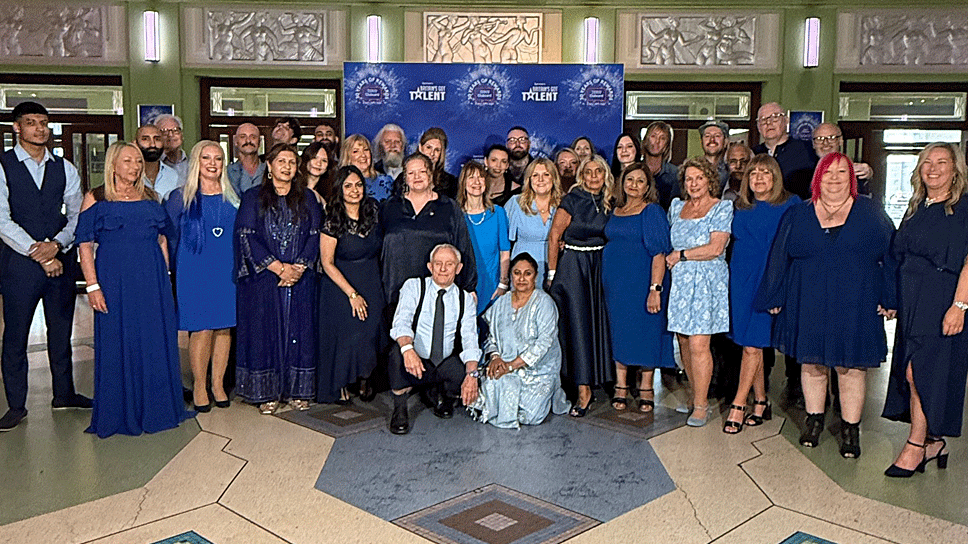Members of Hear Our Voice stood for a photograph. There are about 35 people all of different ethnicities and all wearing different shades of blue.