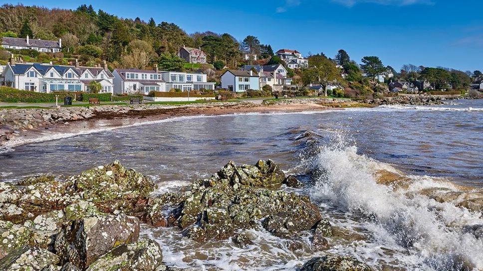 The village of Rockcliffe on the Solway Coast with waves crashing into the shore in front of a row of picturesque houses looking out into the bay