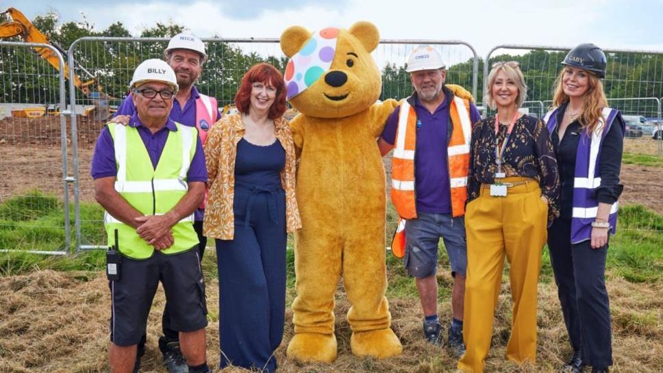Pudsey the Bear and DIY SOS members with Julie on a building site