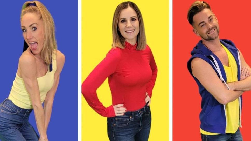 Two women and a man posing against a blue, yellow and red background, respectively. From left, the first woman is wearing a yellow top and jeans, the second woman is wearing a red long-sleeved top and jeans, and the man is wearing a yellow T-shirt and blue gilet and jeans.