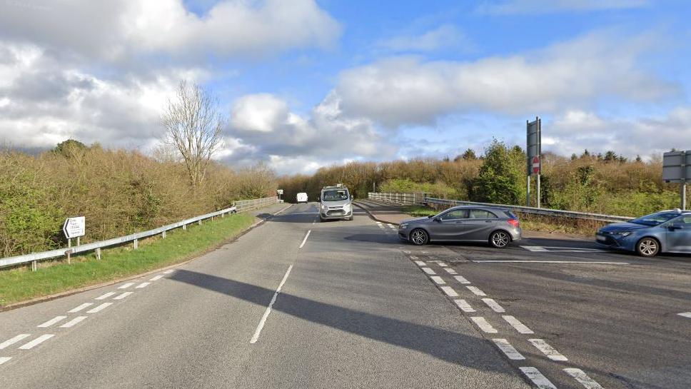 Google Street View of Clay Lane in Chudleigh Knighton with two cars at a slip road junction for the A38 on the left-hand side and a silver van heading towards the camera and a grey van going in the opposite directions.