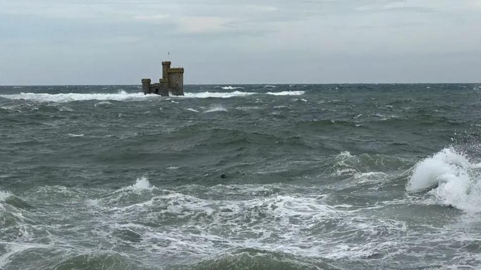Choppy seas with waves breaking around the Tower of Refuge in Douglas Bay.