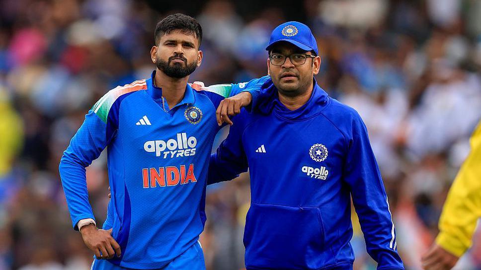 Shreyas Iyer (left) is helped from the field by a member of India's medical staff
