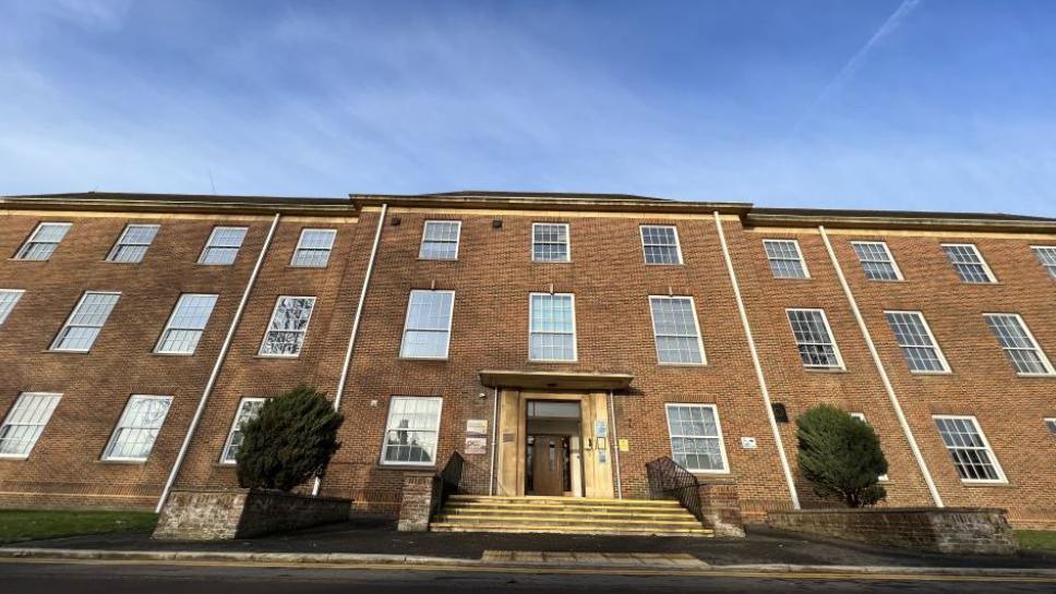 A red brick building with large windows going across, quite traditional