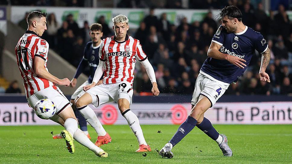 Tristan Crama strikes the ball home with his left foot to score Millwall's second goal as two Stoke City defenders attempt to stop to the French defender