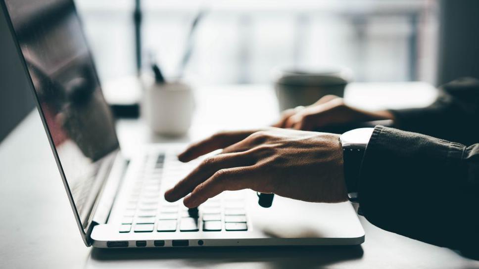 Man typing on a laptop keyboard