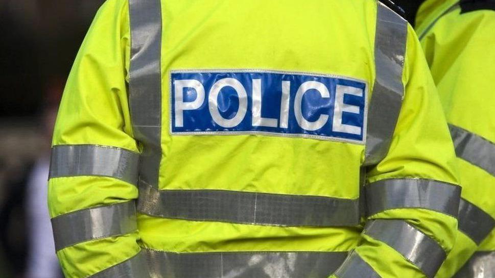 A stock image of a neon yellow police vest with the word police written on the back in white letters on blue background.