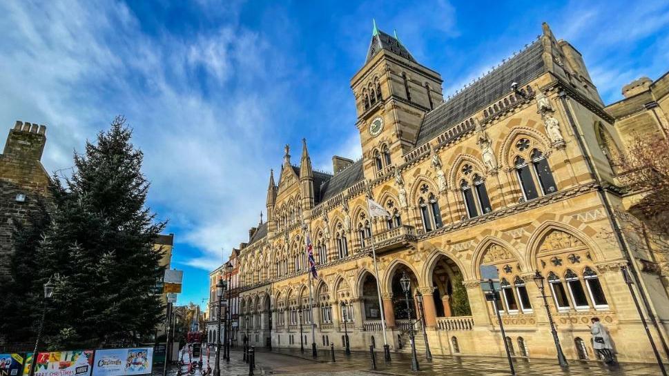 The Guildhall in Northampton. A grand, gothic building with rows of arches and steps leading up to the entrance.