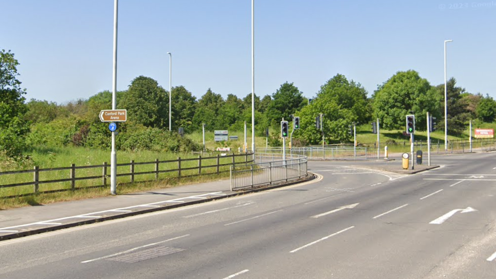 A road junction with a brown sign which reads: "Canford Park Arena"