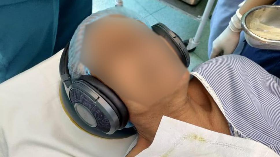 A patient with headphones playing music during surgery in a hospital in Delhi