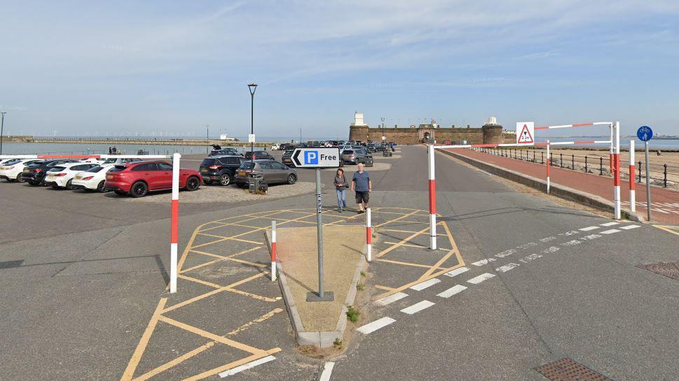 A large car park with Fort Perch Rock castle in the background and the beach. 