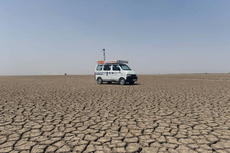 This picture taken on April 7, 2017 shows a 'Zero Connect' programme van driving on parched earth arriving for a tent school workshop with the children of Indian salt pan workers in the Little Rann of Kutch (LRK) region of Gujarat some 180km west of Ahmedabad. The children of Indian salt pan workers, drawn from the Agariya community in Gujarat state, accompany their parents in the remote and arid Little Rann of Kutch (LRK) region for nearly eight months of the year during the salt farming season. The 'Zero Connect' initiative provides basic education for the children in a joint initiative by the Agaria Heet Rakshak Manch, Digital Empowerment Foundation, Internet Society and Wireless for Communities groups. The initiative runs mobile workshops for the children, providing online access and education materials. -- Sheltered beneath a canvas sheet to escape the blistering desert sun, miles from any roads or power lines, a group of Indian children huddle around a digital tablet and experience the internet for the very first time. The remote wi-fi connection is powered by a van bringing the digital world to around 10,000 families living on the inhospitable salt flats of western Gujarat, where they work eight months a year in extreme conditions. (