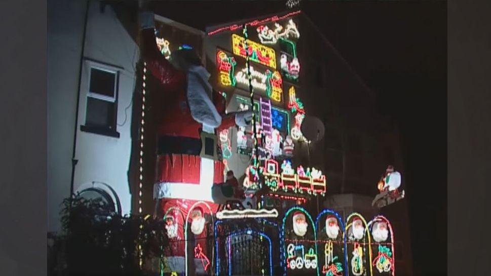 A three storey house decorated in Christmas lights with a giant Father Christmas