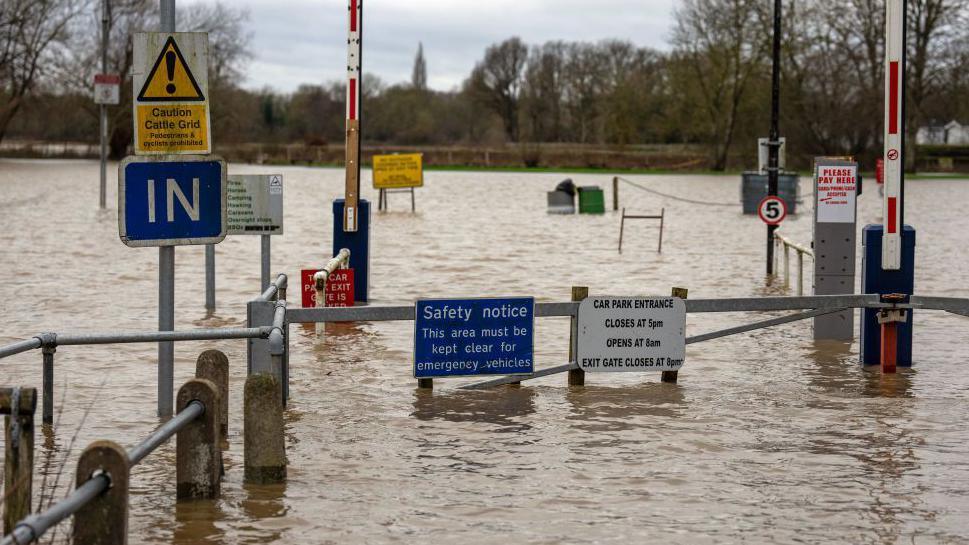 Car park entrance and signs surrounded by flood water